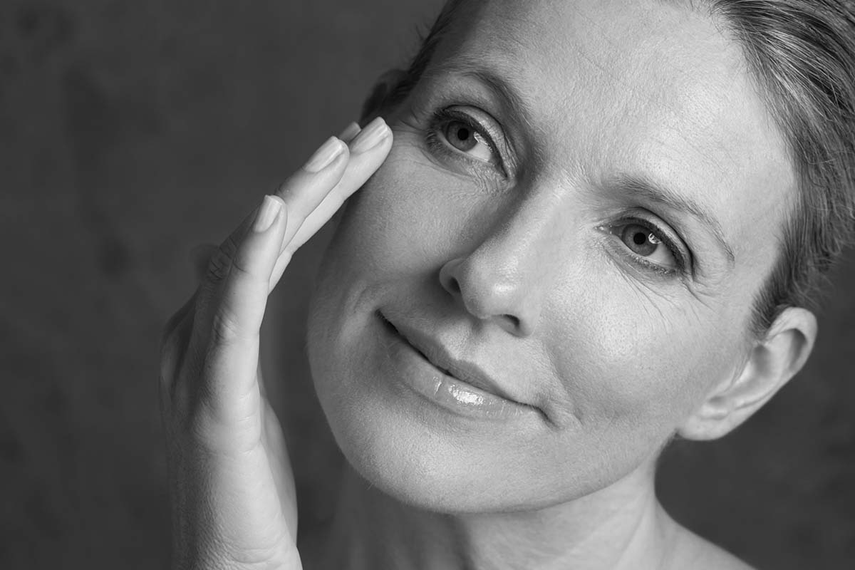 a woman tilts her head and touches her face after eyelid surgery in Dallas