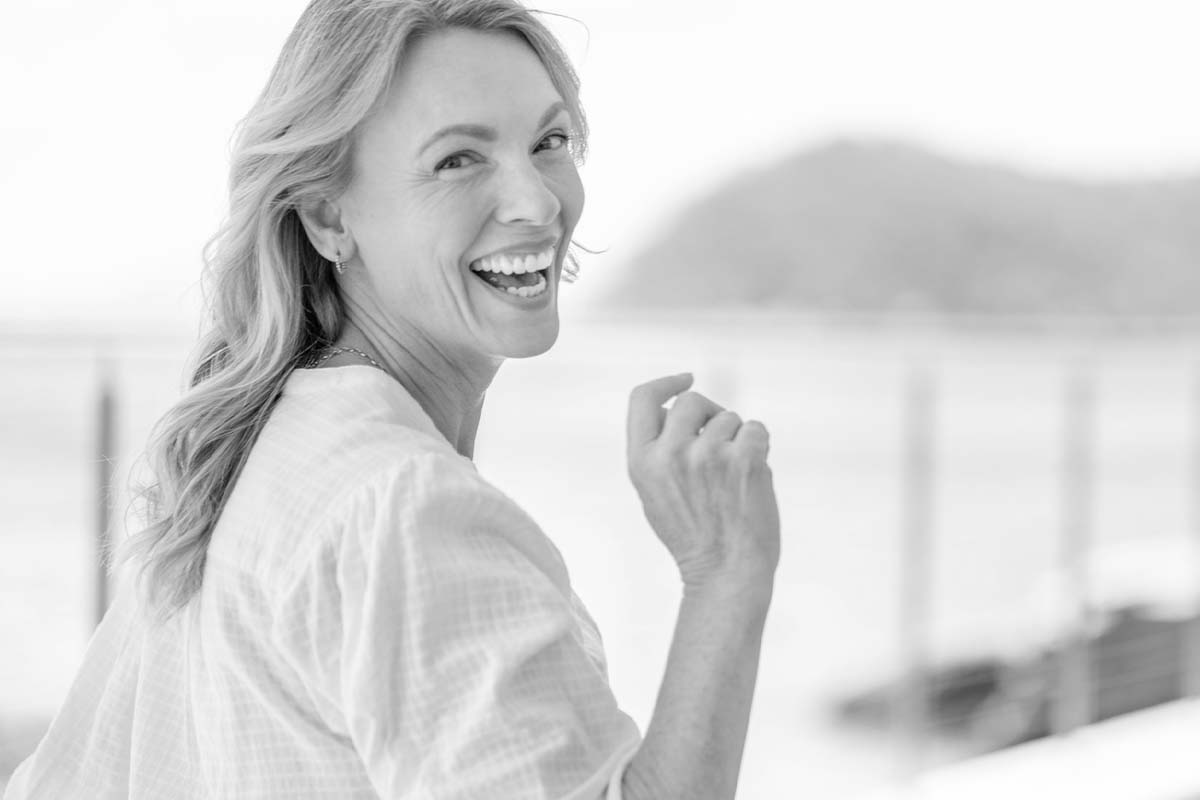 an older woman outside on a dock, her head turned back toward the camera and smiling after a neck lift in Dallas