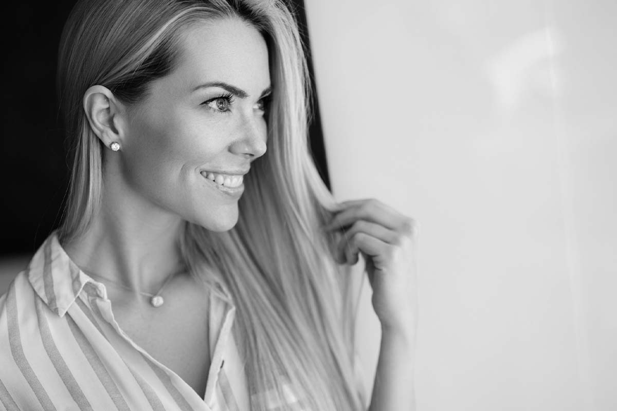 a woman looks out a window while smiling after a facelift in Dallas